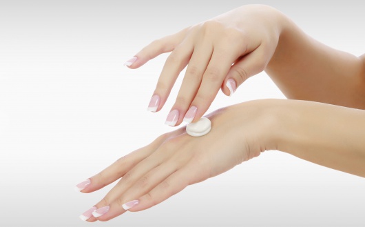 Female hands with a moisturiser on light grey background